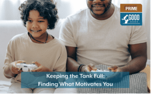 A father and child sit side by side on a sofa smiling and holding video game controllers